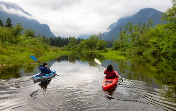 Adventure Friends Kayaking in Kayak surrounded by Canadian Mountain