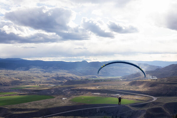Adventurous Man Flying on a Paraglider around the mountains.