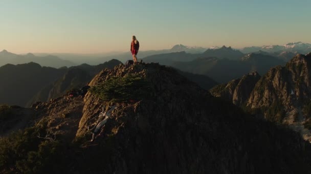 Aventurera mujer caucásica senderismo en la cima de un acantilado de montaña rocosa. — Vídeos de Stock