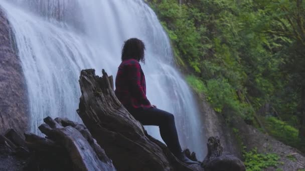 Vrouw kijkt naar de waterval in het Canadese regenwoud. — Stockvideo
