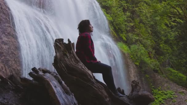 Nő nézi a vízesést a kanadai esőerdőben. — Stock videók