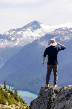 Bir dağ çıkıntısında duran kişi Whistler, BC, Kanada zirvelerini hayranlıkla seyrediyor..