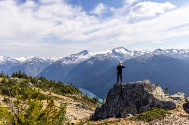 Whistler, BC, Kanada manzaralı dağları olan kayalık zirvede duran kişi..