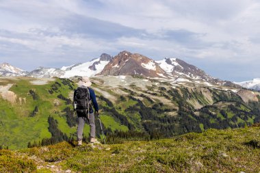 Whistler, BC, Kanada 'daki uçsuz bucaksız dağların ve yeşilliklerin nefes kesici manzarasının tadını çıkaran yürüyüşçü..