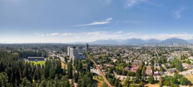 Burnaby şehir manzarasını ve güneşli gökyüzünün altındaki Büyük Vancouver alanını gösteren panoramik bir manzara.