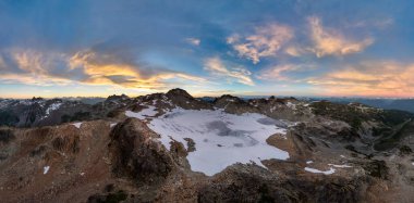 Kanada, BC 'nin doğal manzarasında karlı dağ zirveleri ve canlı günbatımı.