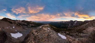 Gün batımında canlı dağ sıraları çarpıcı gökyüzü ve kar parçalarıyla, BC, Kanada.