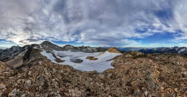 BC, Kanada 'da karla kaplı tepeleri ve bulutlarıyla nefes kesici dağ manzarası.