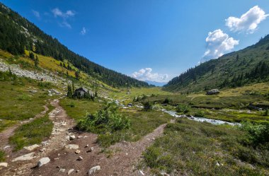Berrak bir nehir, yemyeşil yemyeşil bir vadi ve dağlık bir zemin..