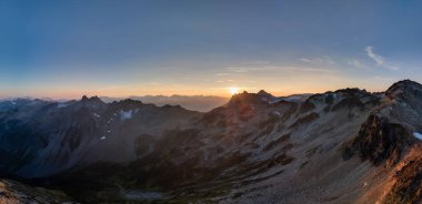 Baş döndürücü bir gün doğumu engebeli dağları aydınlatıyor. BC, Kanada 'nın sakin bir manzarasında..