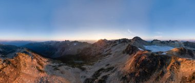 BC, Kanada 'daki engebeli dağların üzerinde güzel panoramik günbatımı manzarası.
