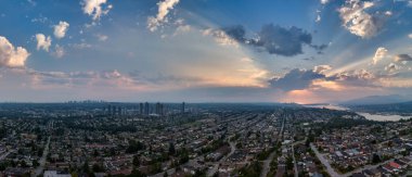 Burnaby, BC 'nin panoramik şehir manzarası, günbatımı gökyüzü ve dağ manzarası.