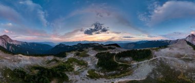 BC, Kanada 'da dağlık arazi ve orman vadileri üzerinde renkli akşam gökyüzü