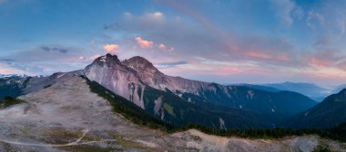 BC, Kanada 'da gün batımında canlı gökyüzü ile dağlık bir arazi manzarası.