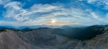 Engebeli dağlık arazide nefes kesen gün batımı dramatik bulut oluşumlarıyla, BC, Kanada.