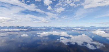 Dağ sıraları ve bulutlu gökyüzü su yüzeyine yansıyor, üç boyutlu bir görüntüde yakalanıyor..
