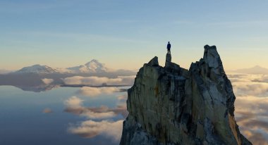 Bir dağ zirvesinin tepesindeki bir insanın nefes kesici görüntüsü..
