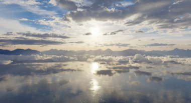 Bulutlar ve yumuşak güneş ışığıyla bir dağın 3D yansıması.