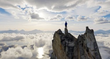 Bulutların üstündeki dağın tepesinde bir adamın çarpıcı üç boyutlu görüntüsü..