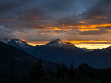 Squamish ve Whistler, BC, Kanada yakınlarındaki karlı dağ tepelerinde altın gün batımı.