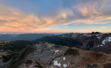 Kanada, British Columbia 'daki engebeli dağların üzerinde gün batımı vadiler, kar ve dramatik gökyüzü..