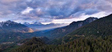 Geniş dağ vadisi, çam ormanları, dramatik bulutlar ve Britanya Kolumbiyası, Kanada 'da güneşli tepeler..
