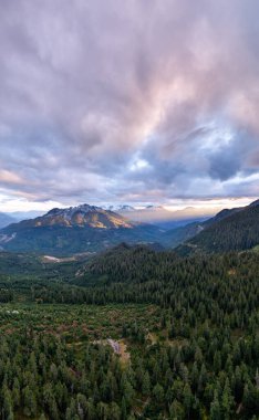 Çam ormanları ve engebeli tepeleri olan Alp Vadisi renkli bir günbatımı altında, Britanya Kolumbiyası, Kanada.