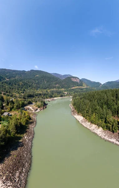 Britanya Kolumbiyası, Kanada 'da kayalık kıyılar ve yoğun ormanlar arasında sakin yeşil bir nehir esiyor.