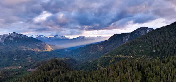 Geniş dağ vadisi, çam ormanları, dramatik bulutlar ve Britanya Kolumbiyası, Kanada 'da güneşli tepeler..