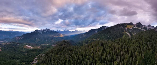 Engebeli dağların panoramik manzarası, sık yeşil ormanlar, ve Britanya Kolumbiyası, Kanada üzerindeki dramatik bulutlar.
