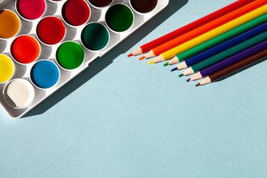 Mavi arka planda renkli kalem ve boyalar