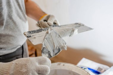 Ev yapımı işçiliği: bir işçi mala sıva doldurur, pürüzsüz paltoyu duvara sürmeye hazırlanır.