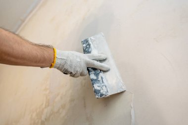 Yüzey hazırlığı devam ediyor: Bir işçi, boyamadan önce en uygun düzlük için iç duvardan yeni alçı ya da alçıyı iterek yayıyor