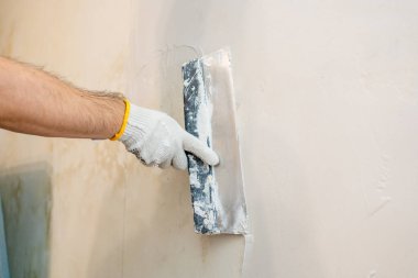 Yüzey hazırlığı devam ediyor: Bir işçi, boyamadan önce en uygun düzlük için iç duvardan yeni alçı ya da alçıyı iterek yayıyor