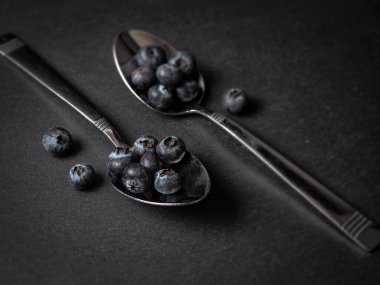 Fresh raw Blueberries on spoon against dark background