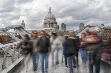 Millennium Footbridge 'de hareket eden ve arka planda Aziz Paul Katedrali olan insanlar.