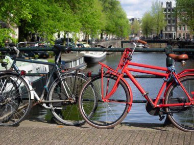 AMSTERDAM, NETHERLANDS - MAYIS 01, 2018: Brouwersgracht kanalı üzerinde arka plan boyunca manzaralı bir köprüye parketmiş bisikletler