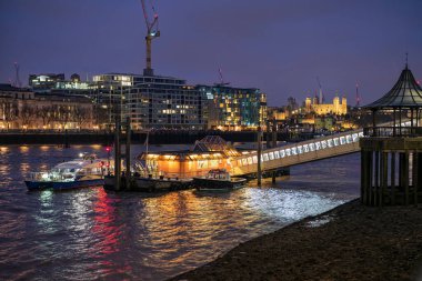 LONDON, İngiltere - 19 Ocak 2019: Londra Köprüsü Şehir İskelesi 'nde bir MBNA Clipper su otobüsü gece aydınlandı