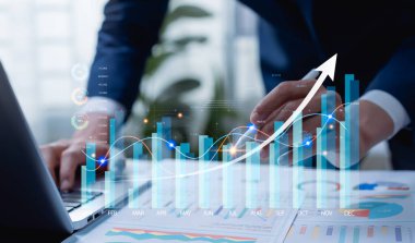 Tablet ve dizüstü bilgisayardaki şirket ölçümlerini analiz eden işadamı, dijital performans gösterge panellerini inceleyen, stratejik planlama, piyasa analizi ve veri odaklı iş kararlarına rehberlik eden iş adamı.