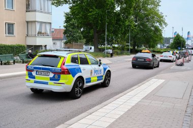 Nynashamn, Stockholm İlçesi, İsveç - 6 Haziran 2025: İsveçli bir polis arabası yolda ilerliyor. Araba beyaz ve mavi, yanında Polis yazıyor.