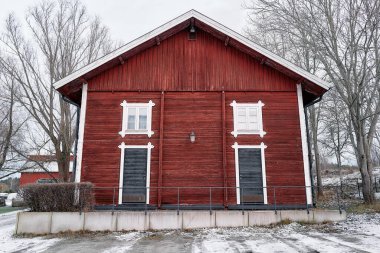 Beyaz çatılı ve beyaz çizgili kırmızı bir ev. Ev ağaçlarla çevrili ve karla kaplı bir garaj yolu var. Haninge, Stockholm, İsveç, 25 Aralık 2025.