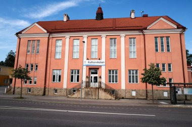 Önünde mavi ve beyaz işareti olan büyük kırmızı bir bina. Bina eski ve bir sürü penceresi var. Nynashamn, Stockholm, İsveç, 25 Mayıs 2025.