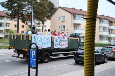 Yüksek lisans öğrencilerinin olduğu bir kamyonun üzerinde NA32 yazan beyaz bir pankart var. Bir grup insan kamyona biniyor. Nynashamn, Stockholm County, İsveç, 06 Haziran 2025.