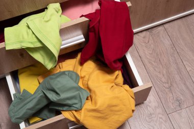 Elbise yığını dolabın açık çekmecesinde yatıyor. Etrafa saçılmış şeyler