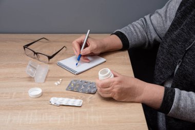 Emekli kadın hapları günlere göre sınıflandırır. Kadın eli hapları ilaç kutularına ayırıyor..