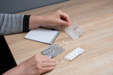 Emekli kadın hapları günlere göre sınıflandırır. Kadın eli hapları ilaç kutularına ayırıyor..