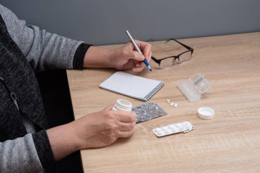 Emekli kadın hapları günlere göre sınıflandırır. Kadın eli hapları ilaç kutularına ayırıyor..