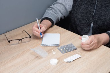 Emekli kadın hapları günlere göre sınıflandırır. Kadın eli hapları ilaç kutularına ayırıyor..