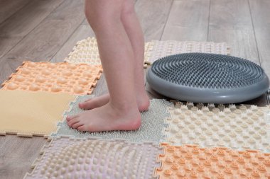 Düz taban için ortopedik masaj minderinin üzerinde duran çocuk ayakları