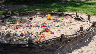 Ekolojik kum havuzu. Çimlerin yanında kum ve oyuncaklar. Kırsal kesimde eğitim, açık bir oyun alanında. Güneşli ve sıcak bir günde eğlence. Aktif çocukluk. Etkin yaşam biçimi